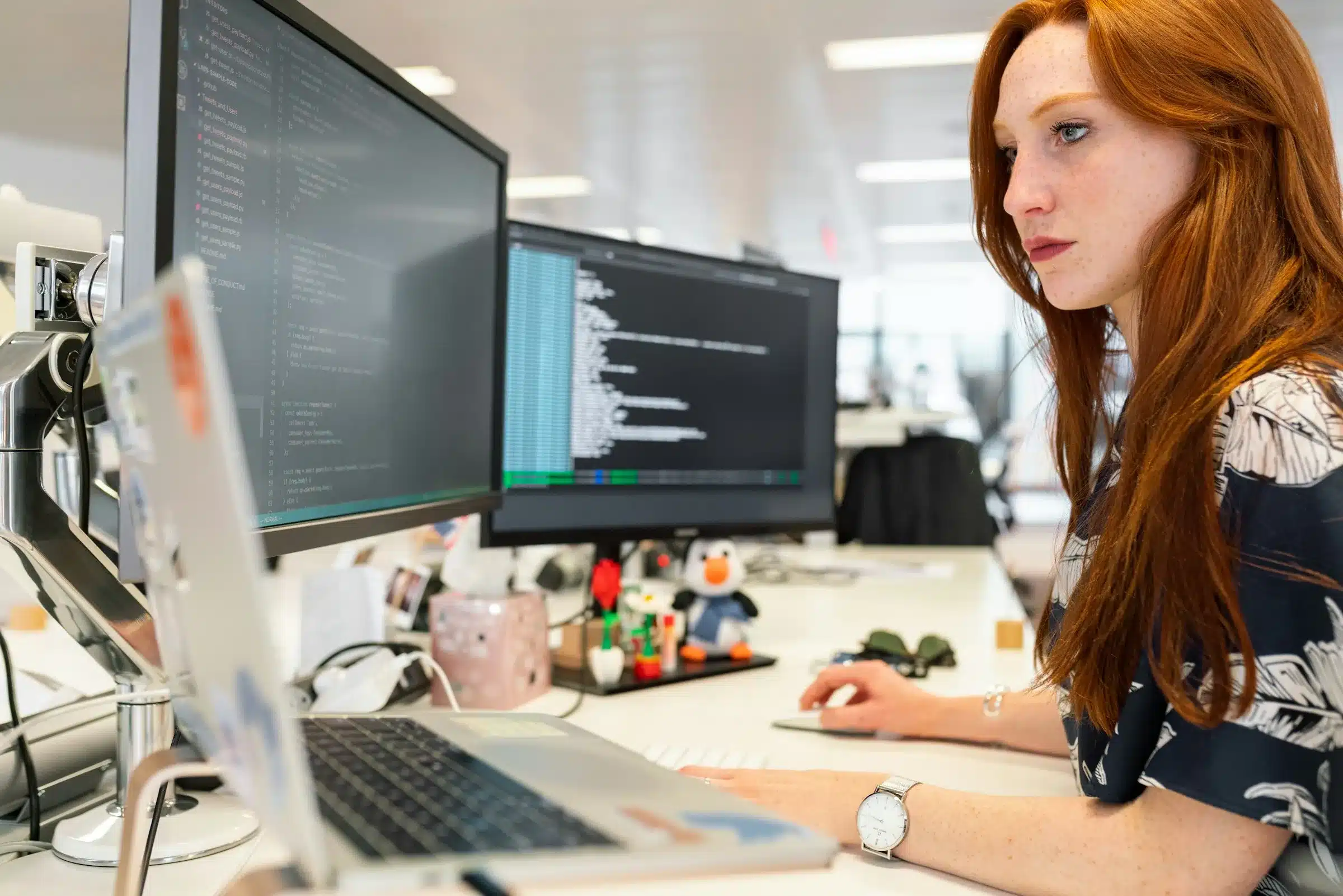 Une personne au travail devant 3 écrans. Concevoir pour et avec les utilisateurs réduit les frictions, favorise l'adoption et donc diminue les risques en cybersécurité. 