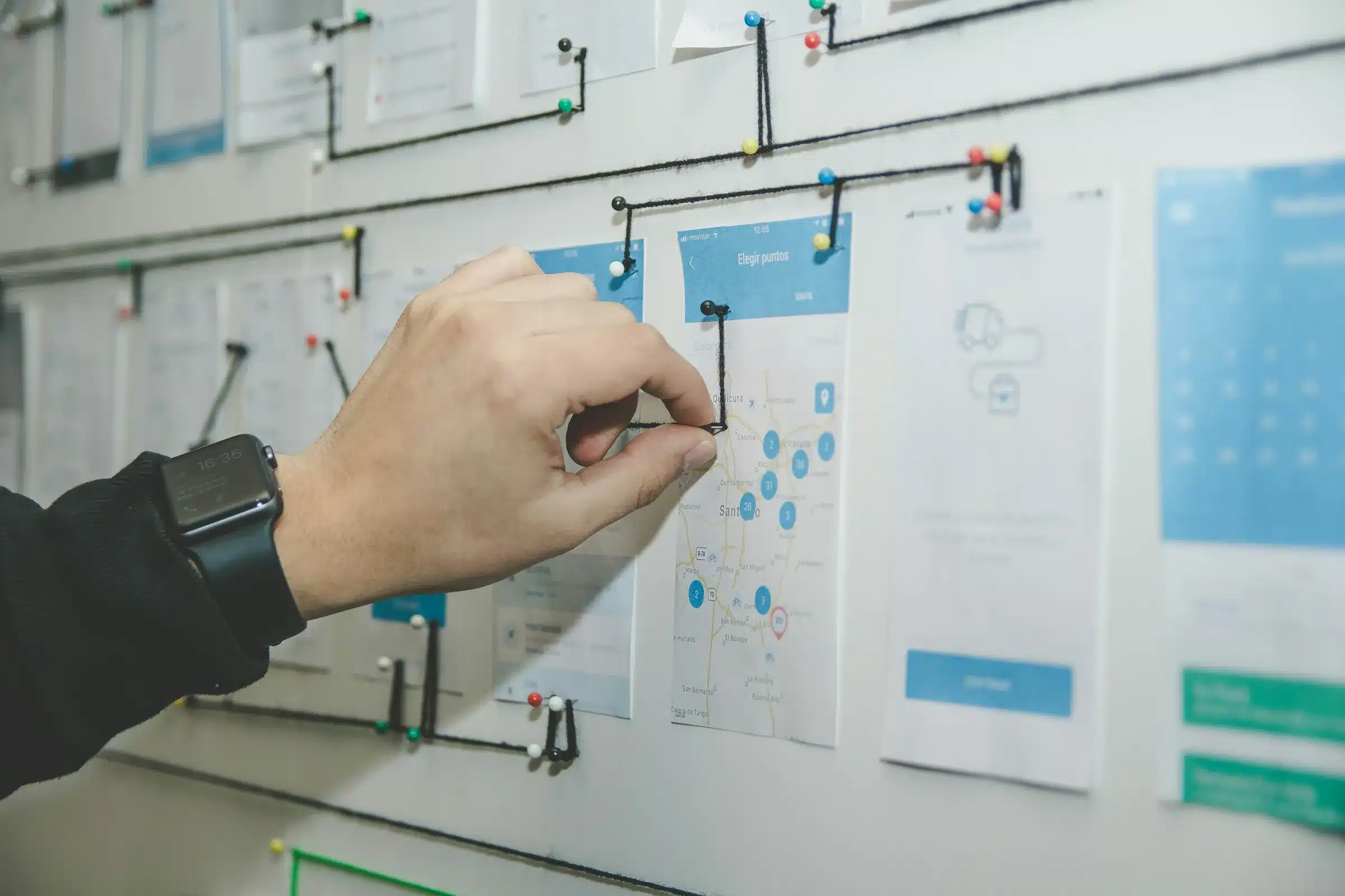 Un UX Designer / Researcher inspecte des écrans impromés sur un mur et les relie entre eux. Il s'assure que les parcours prévus sont adaptés aux attentes et aux besoins des utilisateurs. Il peut révéler les incohérences et s'appuyer sur des bonnes pratiques. Quelles évolutions le métier d'UX Designer va-t-il connaître ?